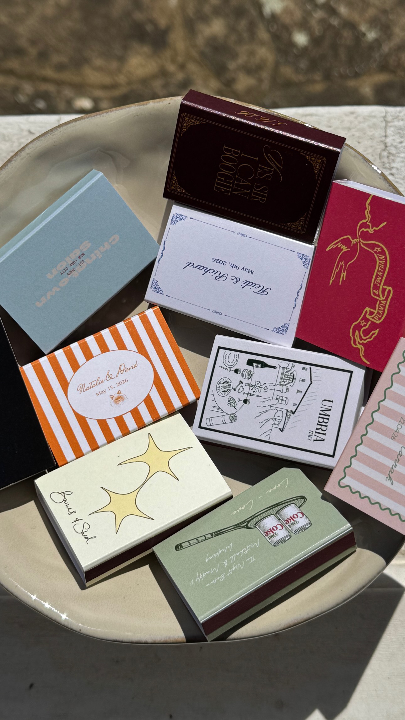 A collection of colourful illustrated matchboxes on a ceramic plate