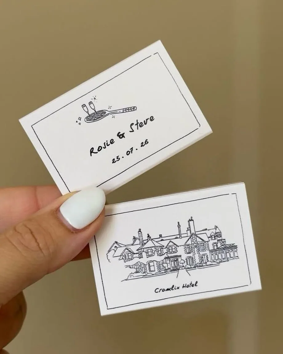 Two illustrated place cards held in hand