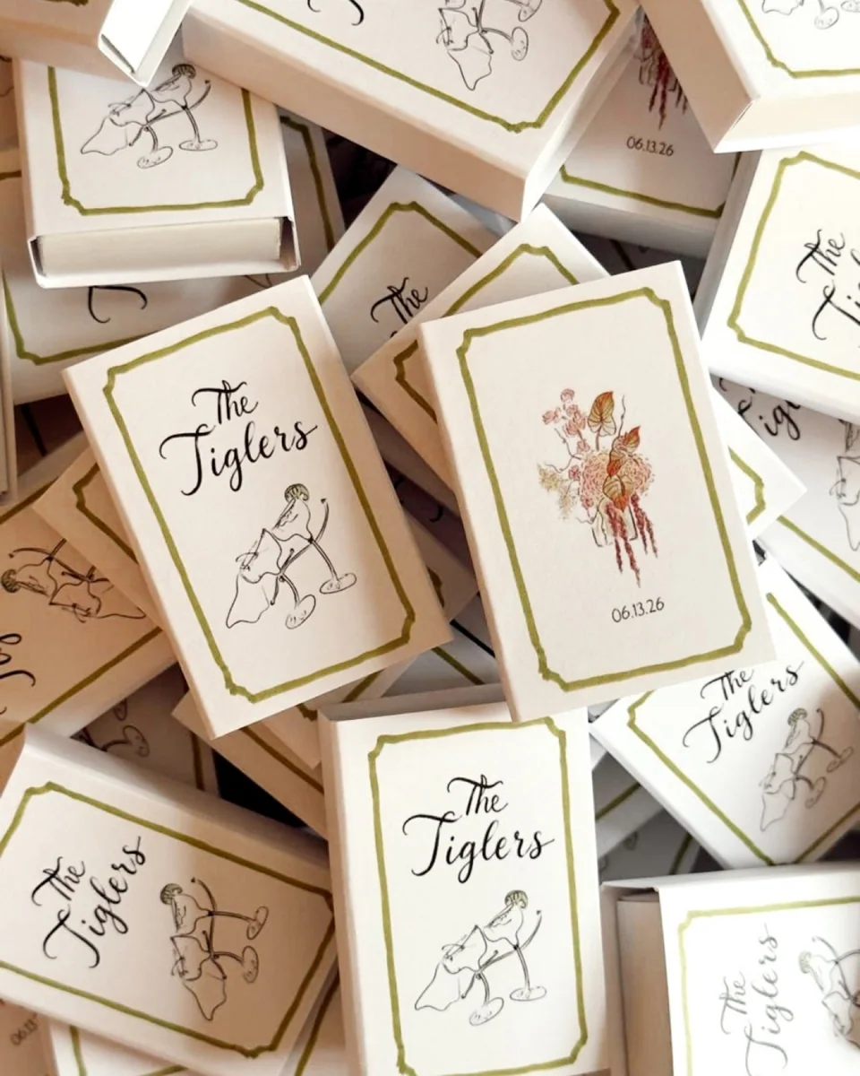 Blue illustrated wedding matchboxes with a venue drawing and swans