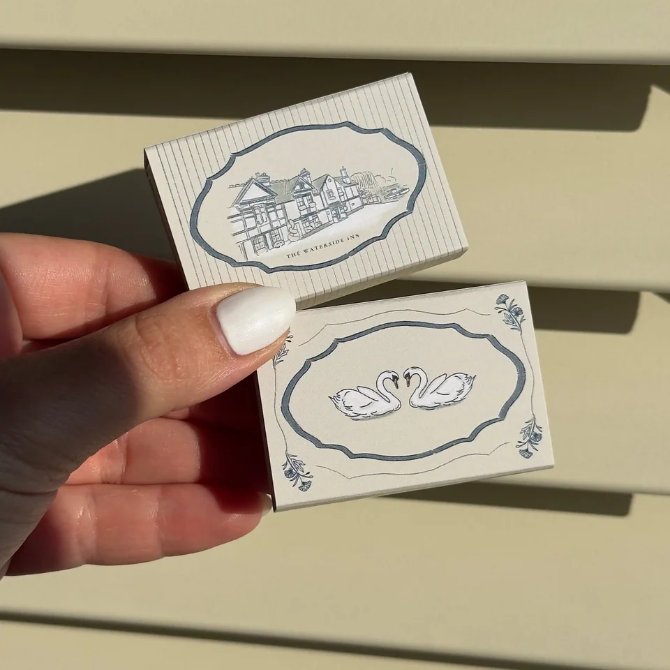 Blue matchboxes illustrated with a venue and two swans